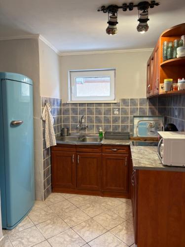 a kitchen with a blue refrigerator and a sink at Napsugár vendégház in Mezőkövesd