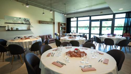 une salle à manger avec des tables et des chaises blanches dans l'établissement Les Villas du Parc de la Chabotterie, à Saint-Sulpice-le-Verdon