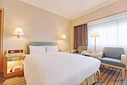 a hotel room with a large bed and two chairs at Santos Hotel in Taipei