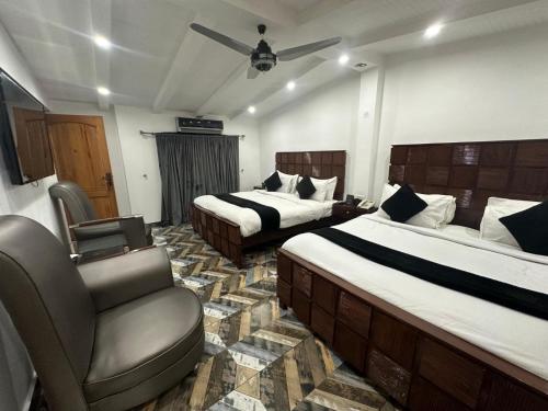a hotel room with two beds and a chair at Lawrence View Hotel, Lahore in Lahore
