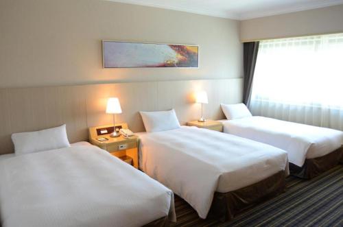 a hotel room with two beds and a window at Santos Hotel in Taipei