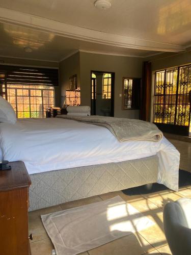 a bedroom with a large bed with white sheets at Inn on Lichfield Lane in Harare