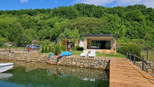 a woman laying on a rock wall next to a lake at Delta Lake House 1 in Velika Reka