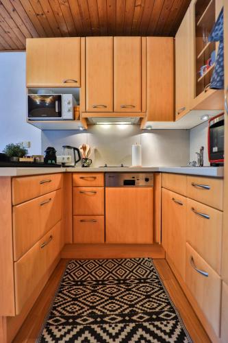 a kitchen with wooden cabinets and a rug at Winzig Apartment in Schladming