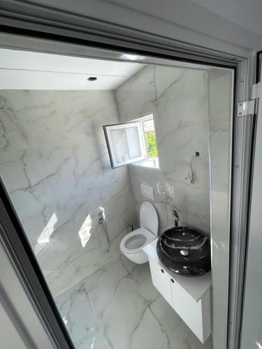 a white bathroom with a toilet and a sink at Oli House 3 in Durrës