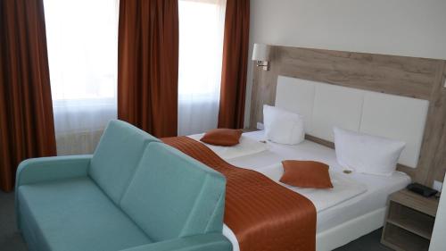a bedroom with a bed and a blue chair at Komfort Hotel Ludwigsburg in Ludwigsburg