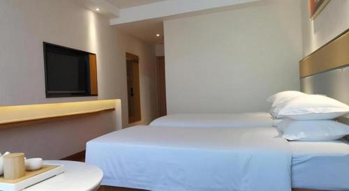a hotel room with two beds and a flat screen tv at GreenTree Inn Geermu Walking Street Business Hotel in Golmud