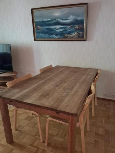 a wooden table with chairs and a painting on the wall at Aalto A - A whole house with 5 bedrooms and a woodburning sauna in Oulu