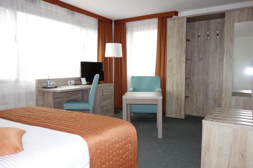 a hotel room with a bed and a desk and chair at Komfort Hotel Ludwigsburg in Ludwigsburg