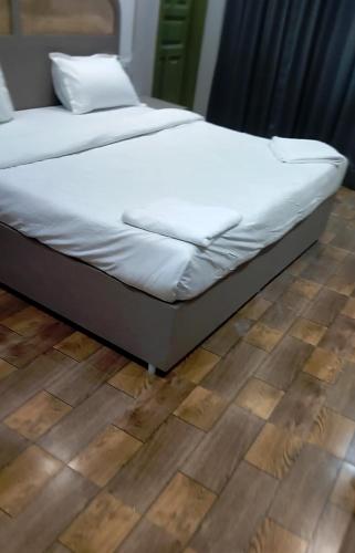 a bed with white sheets on top of a wooden floor at Hotel Spicy Stays in Faridabad