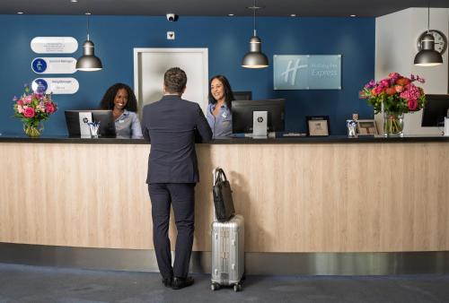 a man standing at a counter with a woman at Holiday Inn Express Geneva Airport by IHG in Geneva