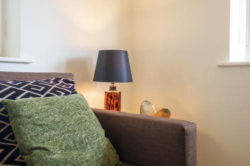 a living room with a couch and a lamp at 2-bedroom apartment in Headington with free parking, walking distance to Oxford Hospitals & Brookes Uni in Oxford