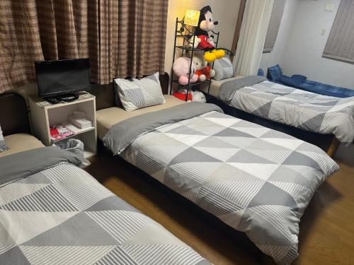Zimmer mit 3 Betten, einem TV und einem TV in der Unterkunft Private Inn Bambee in Kōbe
