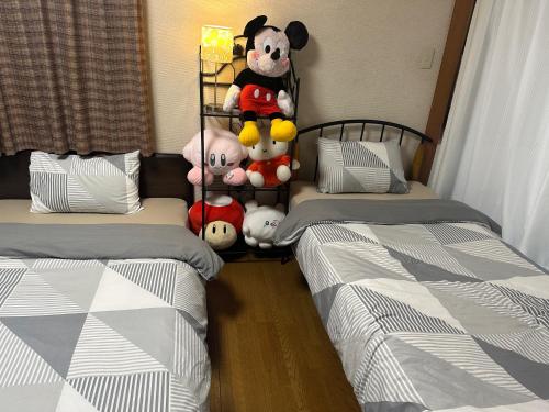 神户Private Inn Bambee的房间里有两张床，架子上放着毛绒玩具