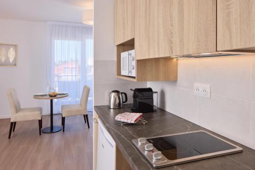 a kitchen with a sink and a table with chairs at Zenitude Hôtel-Résidences Ploërmel in Ploërmel
