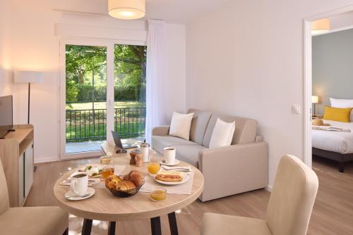 a living room with a table with food on it at Zenitude Hôtel-Résidences Ploërmel in Ploërmel