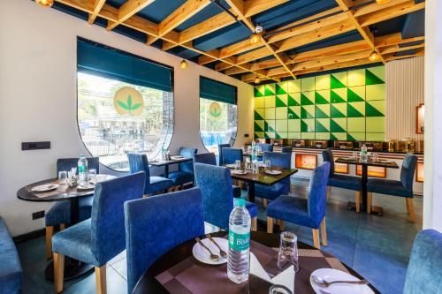 a restaurant with blue chairs and tables andwindows at The SM Hotel By RMR Hotels in New Delhi