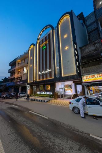 a man standing next to a white car in front of a building at The SM Hotel By RMR Hotels in New Delhi