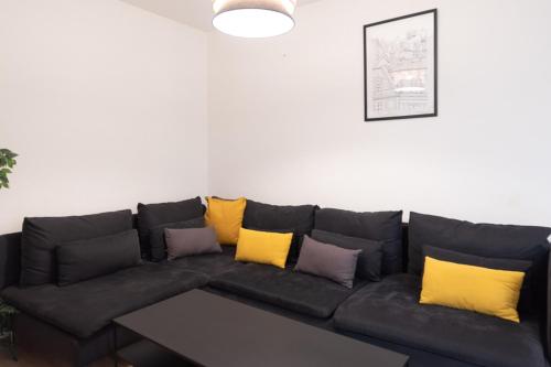 - un canapé noir avec des oreillers jaunes dans le salon dans l'établissement Spacious Apartment near the Champs de Mars, à Paris
