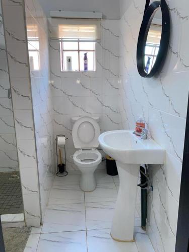 a white bathroom with a toilet and a sink at Inn on Lichfield Lane in Harare