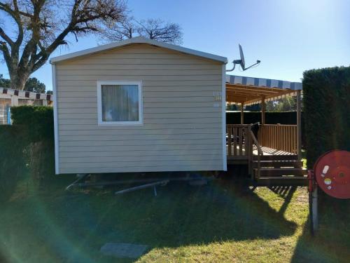 a small shed with a porch and a window at Mobil-Home Bora-Bora in Les Mathes