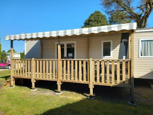 a tiny house with a porch and a deck at Mobil-Home Bora-Bora in Les Mathes