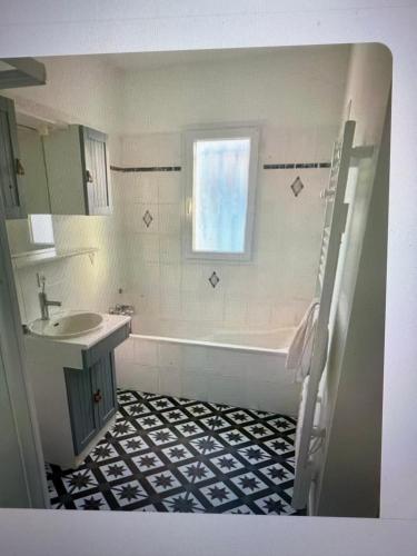 une salle de bain avec une baignoire, un lavabo et une fenêtre dans l'établissement Maison au Vieil à 200m de la mer, à Noirmoutier-en-l'lle