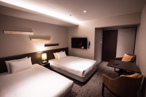 a hotel room with two beds and a television at Rinn Sanjo Ohashi East in Kyoto