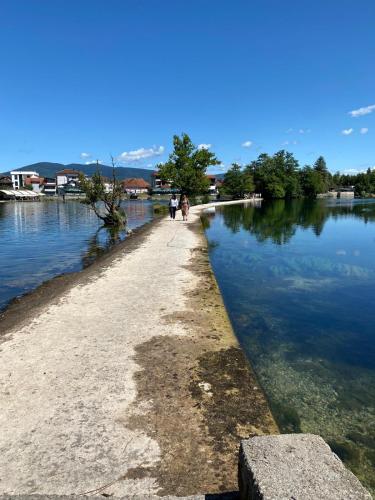 two people walking down a path next to a body of water at Apartments & Rooms Fountain in Bihać