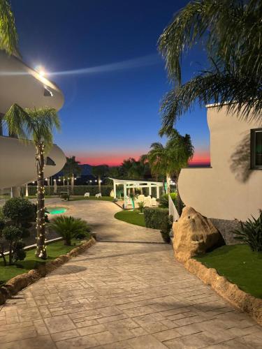 a walkway in front of a building with palm trees at New River Hotel in Borgetto