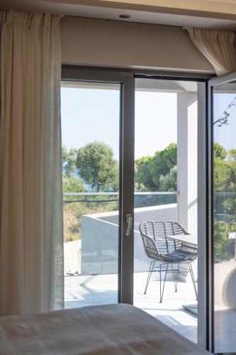 a bedroom with a bed and a balcony with a chair at Zante Sun Resort in Lithakia