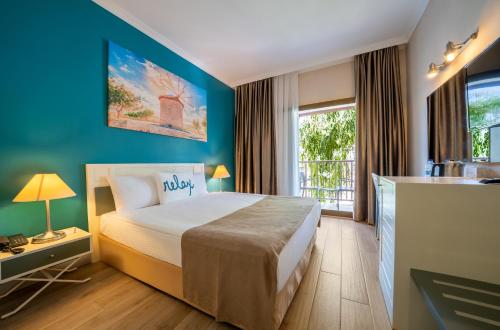 une chambre avec un lit et un mur bleu dans l'établissement Green Bay Resort & Spa - Ultra All Inclusive, à Guvercinlik