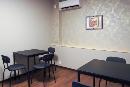 a room with two tables and chairs and a wall at Beer&Guesthouse Nagi in Tanabe