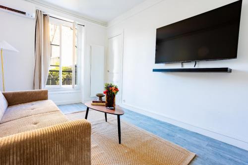 Una sala de estar con un sofá y un televisor. en Appartement Unique , rue du 14 juillet, en Le Pré-Saint-Gervais