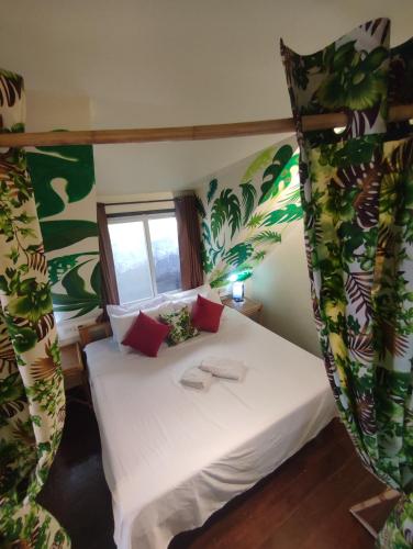 a bedroom with a white bed with green plants at Picado House in El Nido