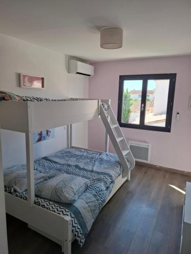 une chambre avec un lit superposé et une fenêtre dans l'établissement Charmante maison au cœur de Valergues avec piscine, à Valergues