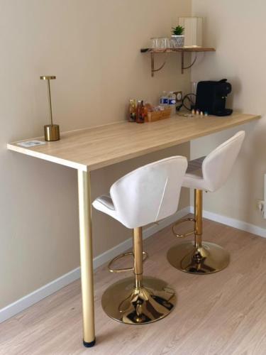 a wooden desk with two white chairs and a table at De Marbre et D or entre le futuroscope et le parc du Puy duFou in Boësse