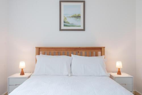 a bedroom with a white bed with two lamps at 2-bedroom apartment in Headington with free parking, walking distance to Oxford Hospitals & Brookes Uni in Oxford