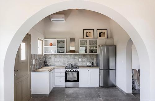 an arched kitchen with white cabinets and a refrigerator at Villa Vathi in Vathí