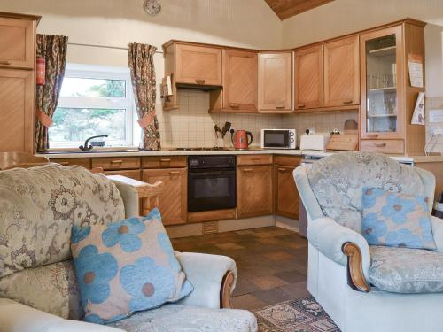 Una sala de estar con dos sillas y una cocina. en The Cottage Gallt Y Balch, en Bodorgan