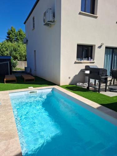 une piscine devant une maison dans l'établissement Charmante maison au cœur de Valergues avec piscine, à Valergues