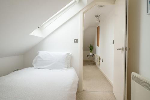 a bedroom with a white bed and a staircase at 2-bedroom apartment in Headington with free parking, walking distance to Oxford Hospitals & Brookes Uni in Oxford