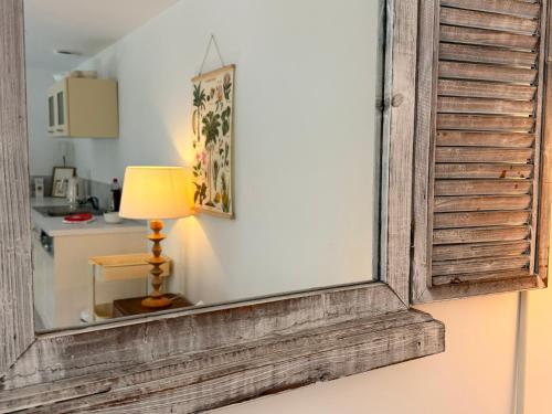 Un espejo en una pared con una lámpara y una cocina. en L Escapade Cœur de Sologne, en Bracieux