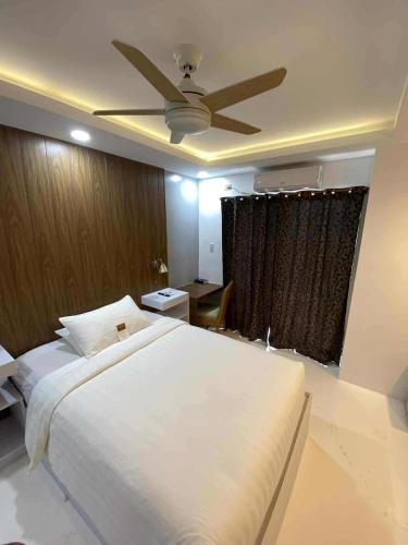 a bedroom with a white bed with a ceiling fan at Buena Casa Hotel in Olongapo