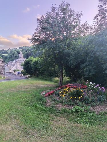 a garden with flowers and a tree in a field at Tulipe, appartement 5 personnes, entre Sancy et Volcans d'Auvergne in Orcival