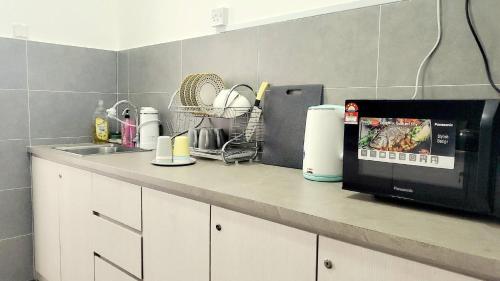 a kitchen counter with a microwave and a sink at Ipoh Cove Hillside Mini Waterpark Family Suite in Ipoh