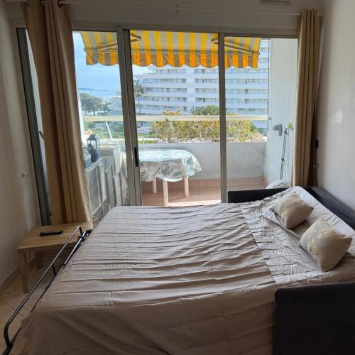 un grand lit dans une chambre avec une grande fenêtre dans l'établissement Appartement Vue sur la mer à 5 minutes des plages, à Villeneuve-Loubet