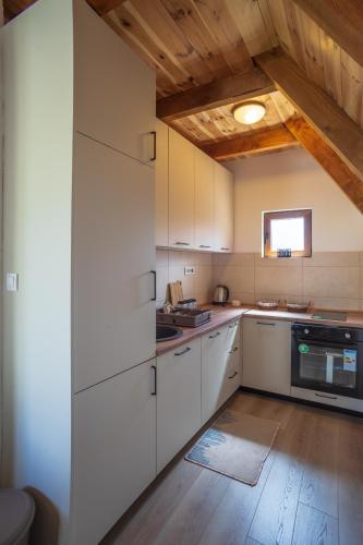 a kitchen with white cabinets and a wooden ceiling at House Maša in Žabljak