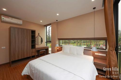 a bedroom with a large white bed and a window at Green Villa 5 phòng ngủ ở Flamingo Đại Lải Resort in Phúc Yên