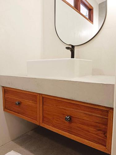 a bathroom with a white sink and a mirror at Baan Varintorn Suanphueng in Suan Phung